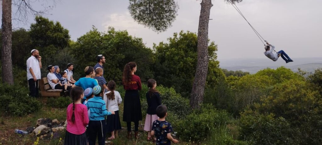 נדנדה על עץ ביער, ובשטח מתאספת המשפחה