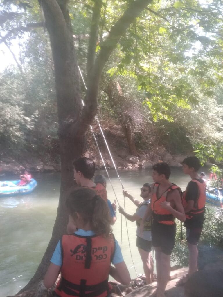 נדנדת חבל על עץ מעל הנחל, והילדים עומדים בתור